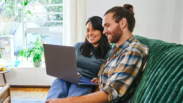 young couple relaxing together while using their laptop